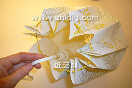 第六步由于现在手工纸艺折纸灯罩在基本的塑形上面已经出现了，所以可以将灯泡放到里面看看效果