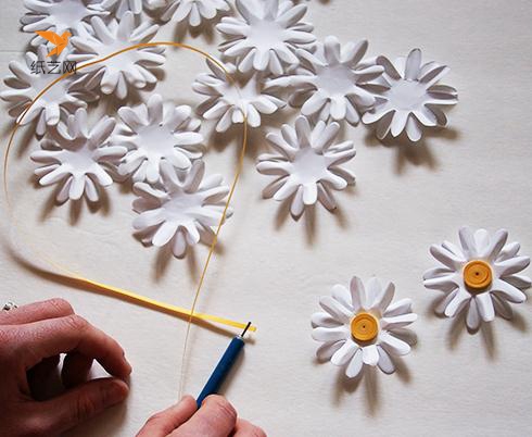 用黄色的衍纸纸条卷成圆形，用白胶粘在花朵的中间就可以制作好一朵小雏菊的花朵啦