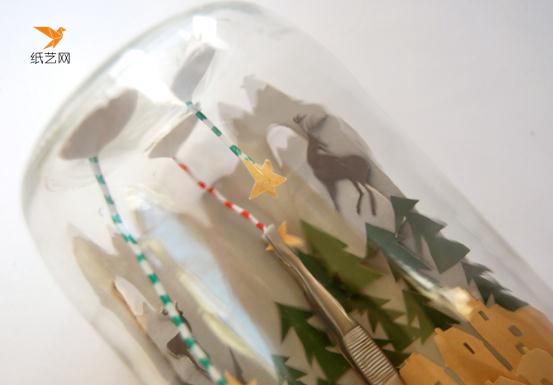 用镊子帮助，将小星星粘到玻璃瓶的瓶底，并且将雪山放到玻璃瓶里面