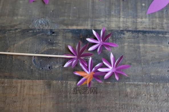 先将彩纸剪成八瓣的花朵，最小的花朵剪出四朵，然后用竹签辅助将花瓣制作出立体感
