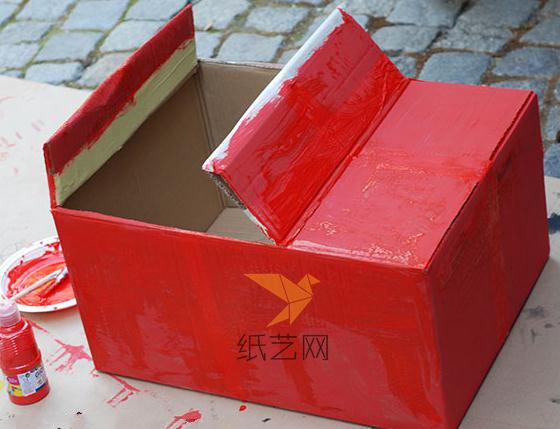让孩子在纸箱外面涂上红色的颜料