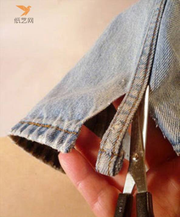 用剪刀剪下旧牛仔裤的拼缝部位
