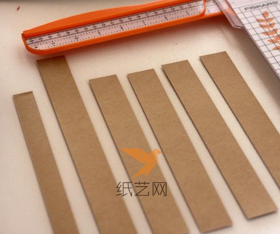 先把牛皮纸裁成同样宽度的四根纸条，一条窄的纸条和一条长的纸条