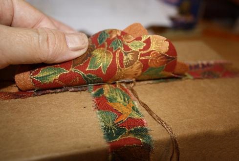然后再用针线缝到礼物上面的包装布条的中间