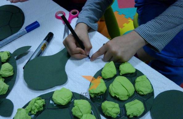 用白纸画出乌龟的眼镜，用绿色厚纸剪成乌龟脑袋和手脚