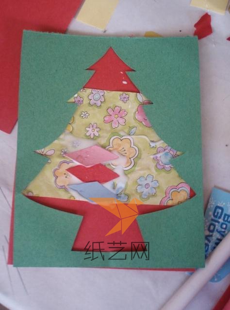 把剪掉中间圣诞树的绿色纸张可以粘到有装饰的红色纸张上面，那就是另外的一种圣诞树的圣诞节贺卡啦。