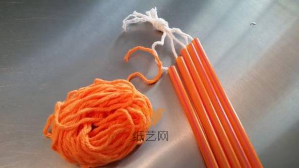 把橘色的毛线系到上面打结的第一根毛线上面