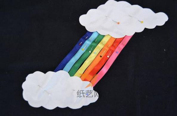 用珠针将云朵和彩虹固定到布料上面的合适的位置