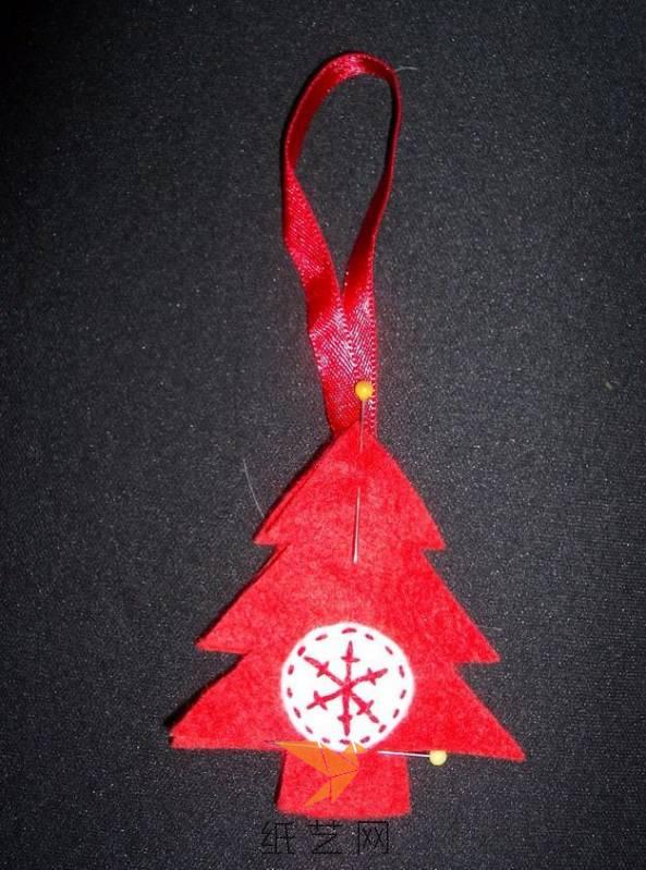 把红色的不织布剪成圣诞树的样子，前后叠放，然后上面夹好丝带，用珠针固定一下