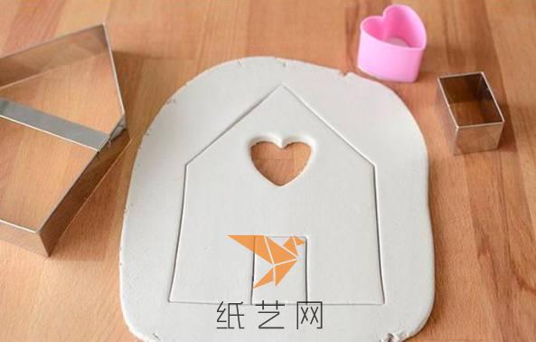 把白色的粘土擀成薄片，然后印出小房子来，在上面用心形的模具印上一个心形