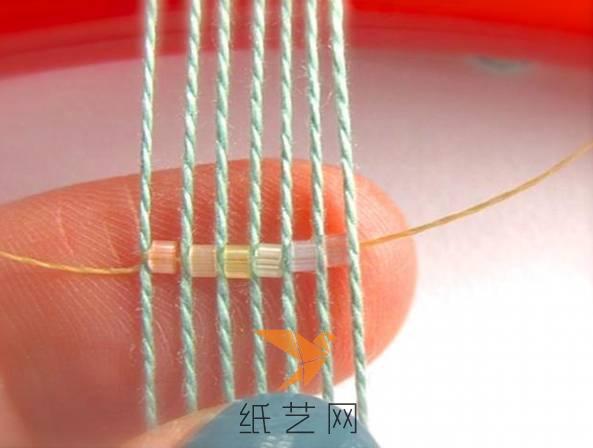 绳子一端在最左边的绳子上面绕一下固定，然后将珠子用手指固定到棉线之间