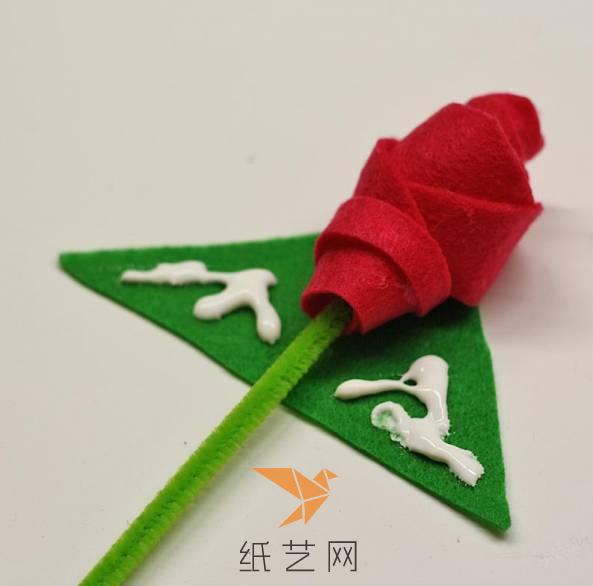 将玫瑰花放在三角形不织布的中间，然后两边涂上白乳胶