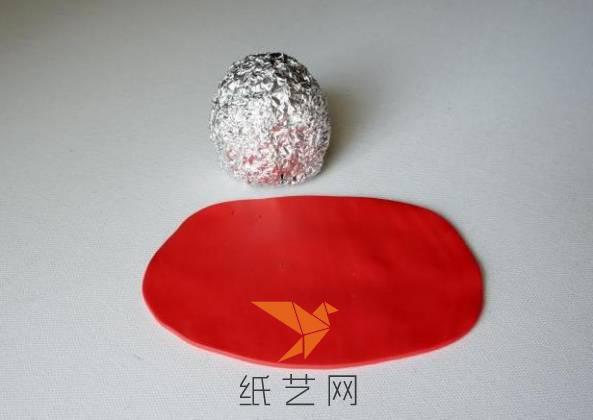 然后将红色的粘土擀成薄片，要能把锡箔纸的球包起来