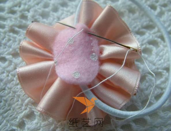 然后用针线将不织布缝在丝带花的背面，这样就可以遮住丝带花和发圈连接的位置了