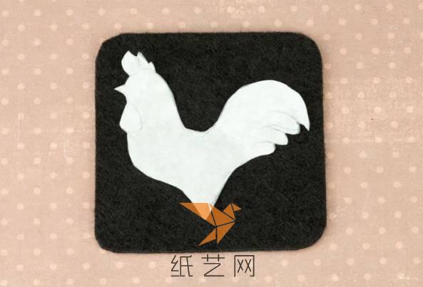 先用白纸剪出一个大公鸡来，放在黑色的不织布上面