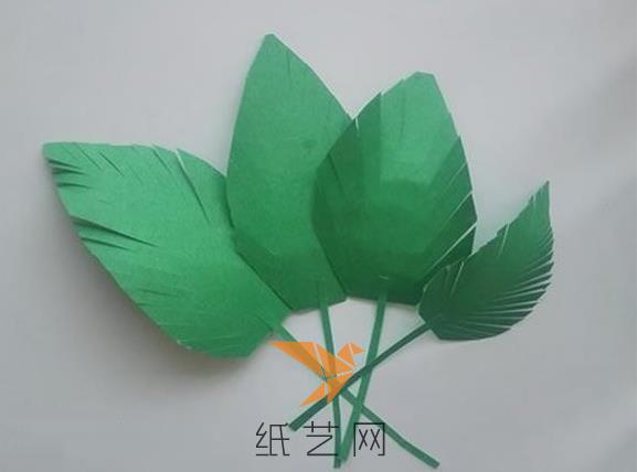 然后将绿色的纸张剪成叶子的样子，粘到绿色彩纸卷成的叶柄上面