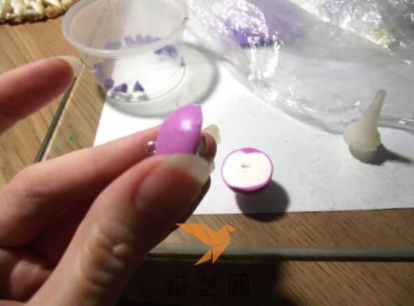 下面就可以用超轻粘土捏成圆球，然后在外面包一层紫色的粘土，将粘土球切成两半，然后在其中一半中间插上固定耳环的金属丝