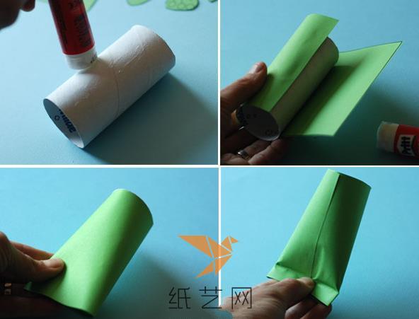 先来用绿色的方形纸张将卫生纸筒的外面包上一层，然后将一端捏扁粘好