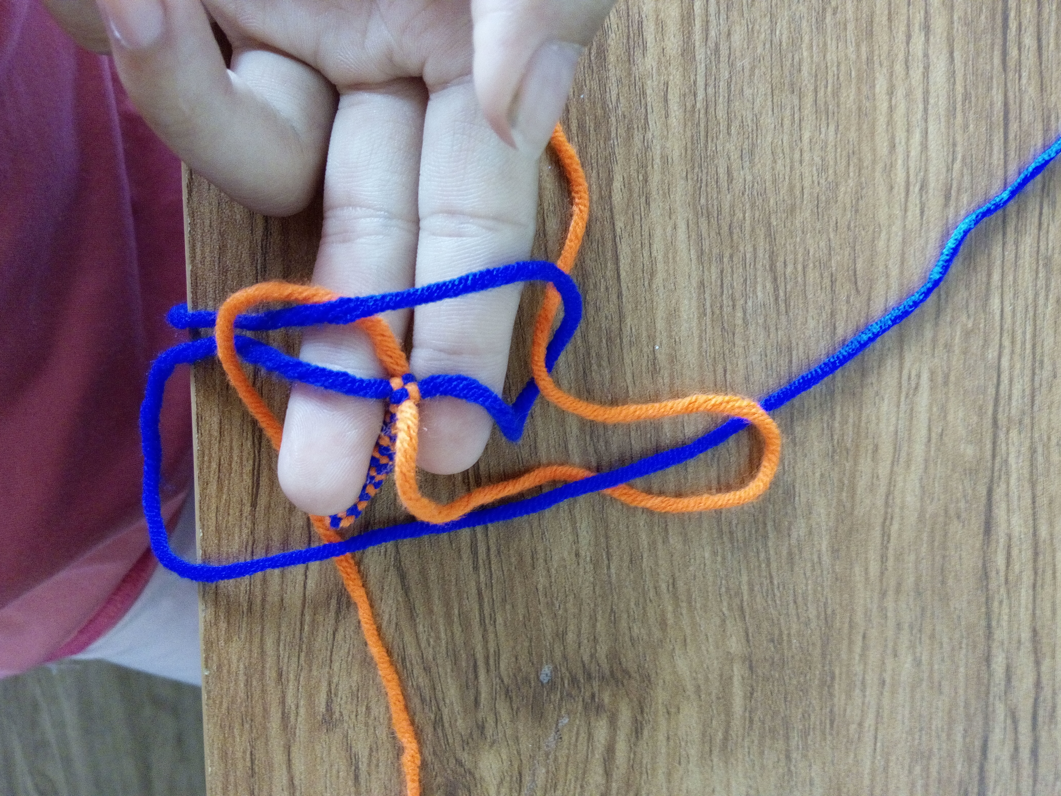 步骤五：左面蓝色的线穿过第一个打出来的环。就是下面橘色压右面蓝色所产生的那个环。步骤二提到过。